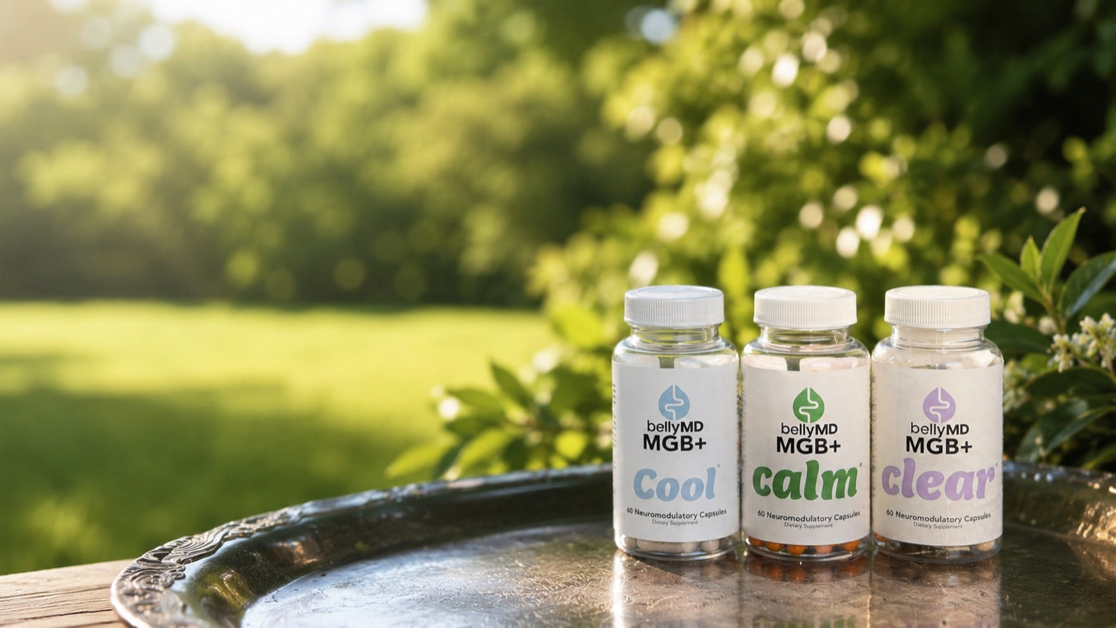 MGB+ Cool, Calm, and Clear bottles on a silver tray in a sunlit garden