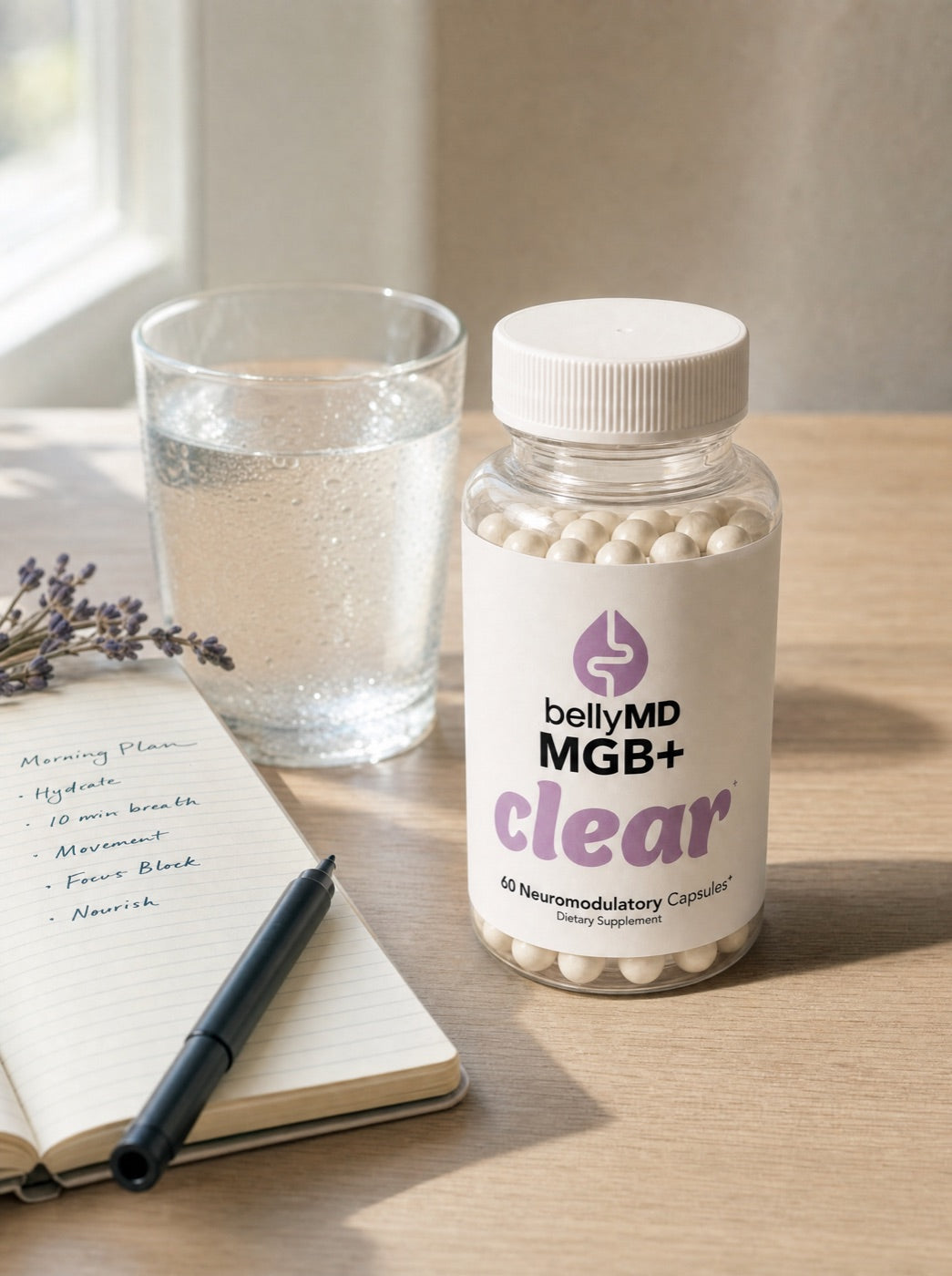 A morning desk with a glass of water, a notebook with a morning plan, and a bottle of MGB+ Clear