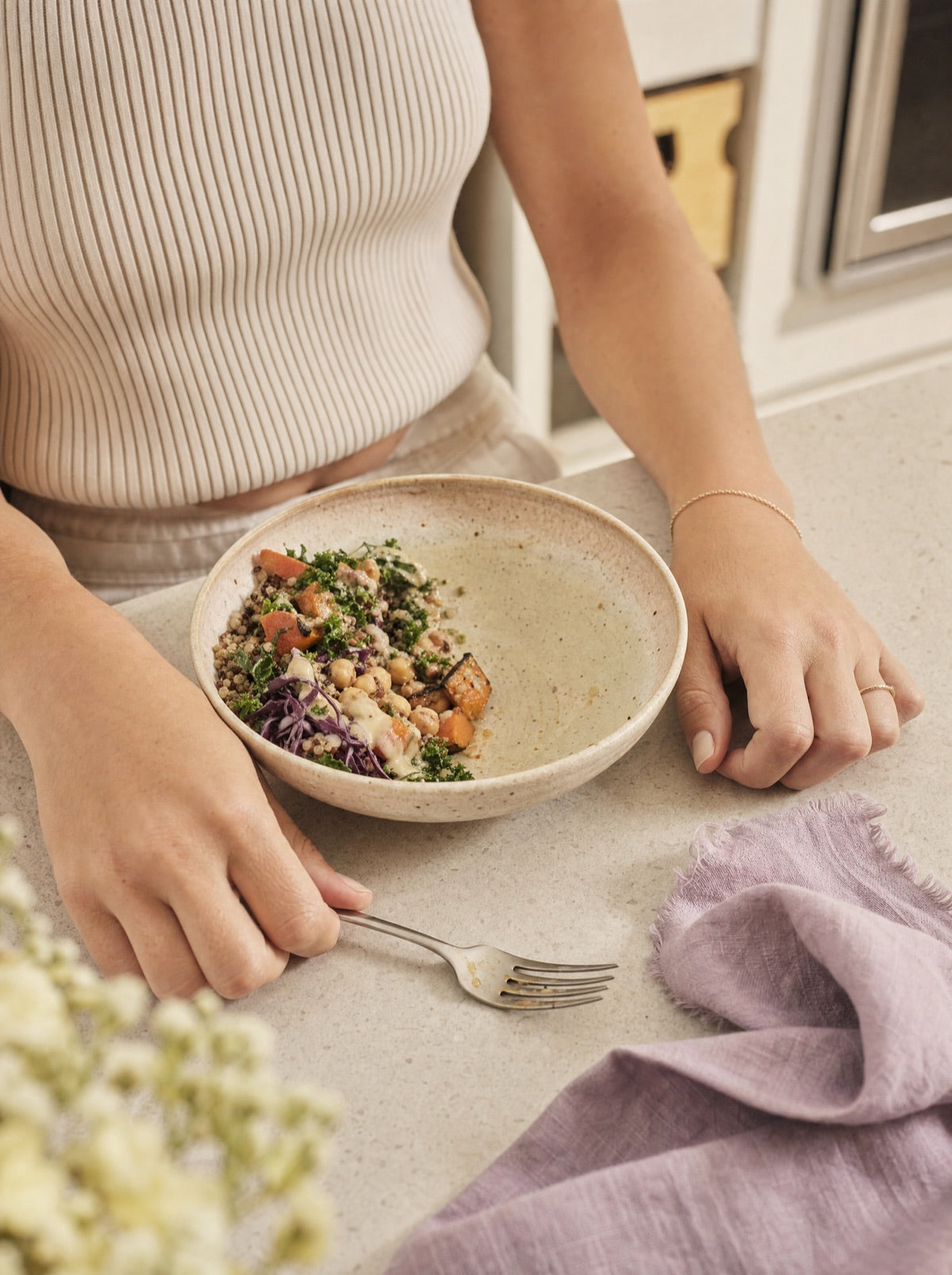 A half-eaten grain bowl on a kitchen counter with a fork resting